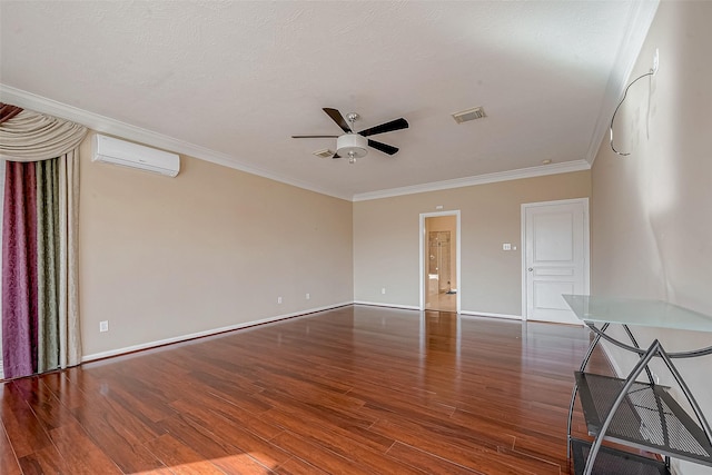 empty room featuring visible vents, a wall unit AC, ornamental molding, wood finished floors, and a ceiling fan