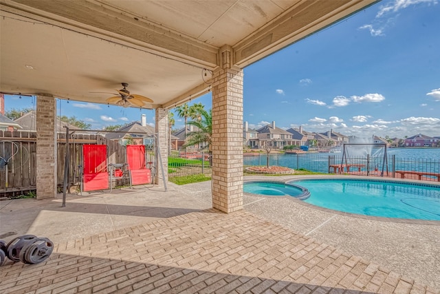 view of swimming pool with a patio, a ceiling fan, a fenced backyard, a pool with connected hot tub, and a residential view