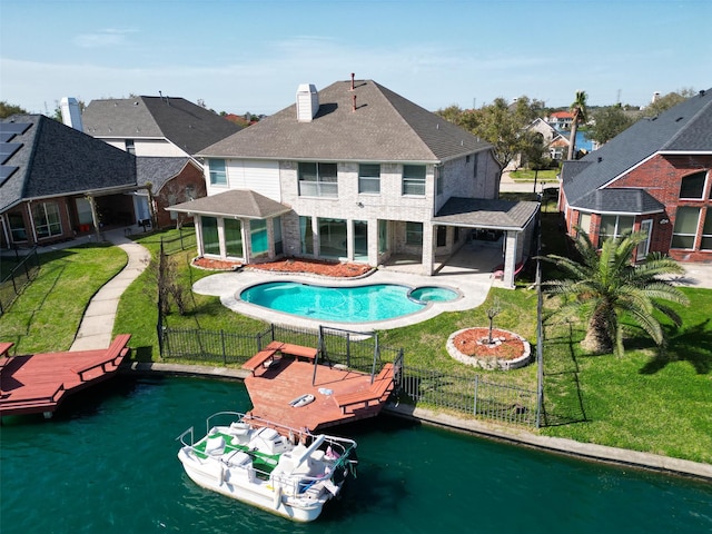 rear view of house with a yard, a patio, a fenced backyard, and a water view