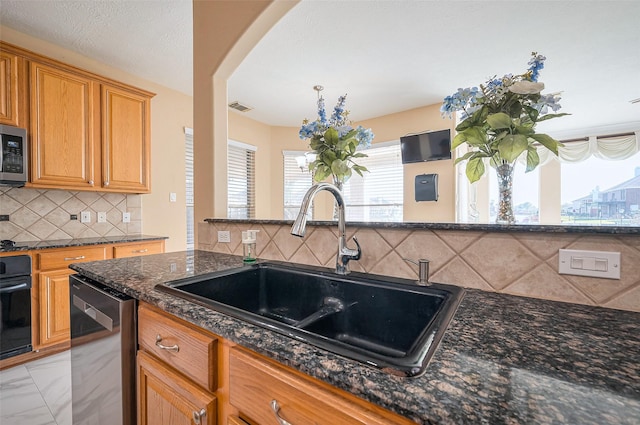 kitchen with visible vents, dark stone countertops, appliances with stainless steel finishes, marble finish floor, and a sink