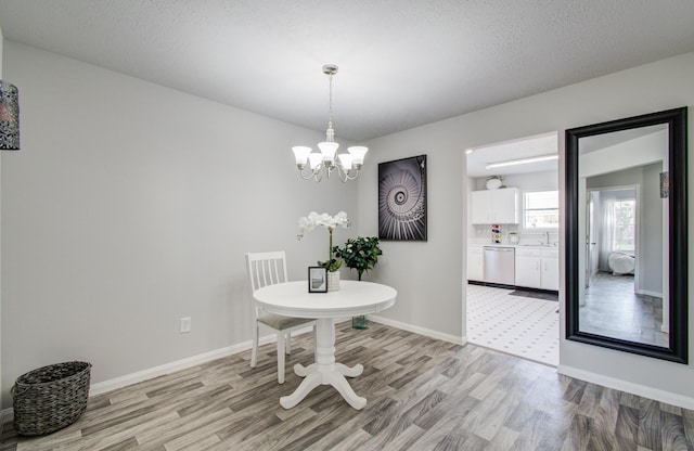 dining area featuring baseboards, light wood-type flooring, and a notable chandelier