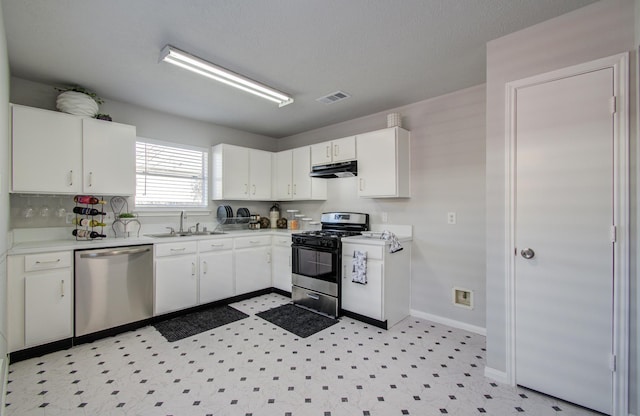 kitchen featuring visible vents, range with gas stovetop, stainless steel dishwasher, under cabinet range hood, and a sink