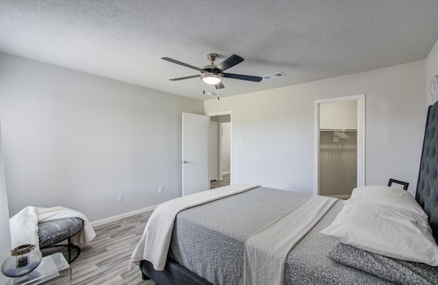 bedroom featuring baseboards, visible vents, ceiling fan, a textured ceiling, and light wood-type flooring