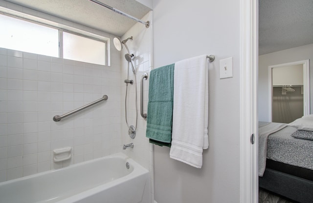 ensuite bathroom featuring a textured ceiling, shower / bathtub combination, and ensuite bath