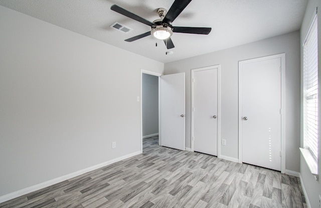 unfurnished bedroom featuring light wood-style floors, visible vents, baseboards, and a ceiling fan