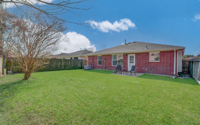 rear view of house featuring a fenced backyard, central AC, brick siding, a yard, and a patio area