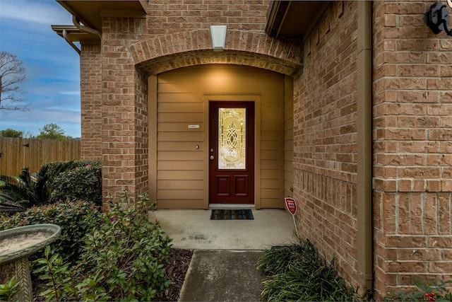 property entrance with brick siding and fence