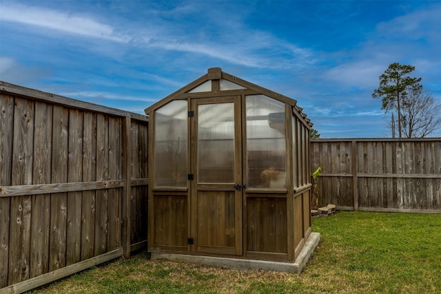 view of greenhouse featuring a yard and a fenced backyard