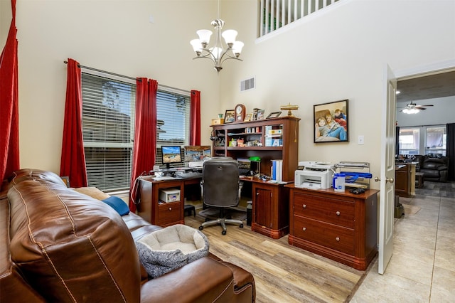 office with a notable chandelier, light wood-style floors, visible vents, and a towering ceiling