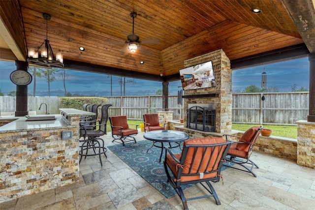 view of patio / terrace with outdoor wet bar, area for grilling, fence, and an outdoor stone fireplace