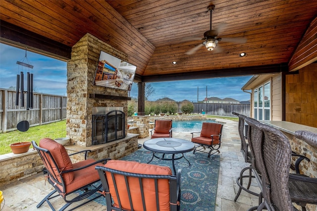 view of patio featuring ceiling fan, a fenced in pool, an outdoor stone fireplace, and a fenced backyard