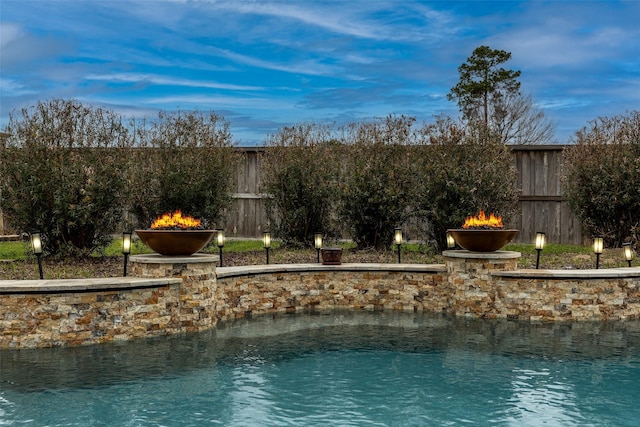 property view of water featuring a fire pit and a fenced backyard