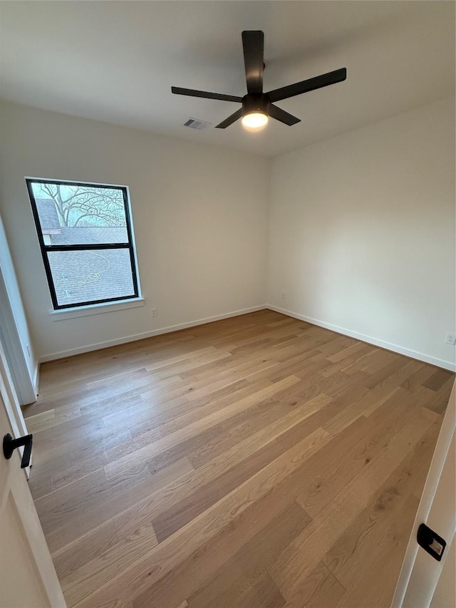 unfurnished room featuring light wood-style flooring, a ceiling fan, visible vents, and baseboards