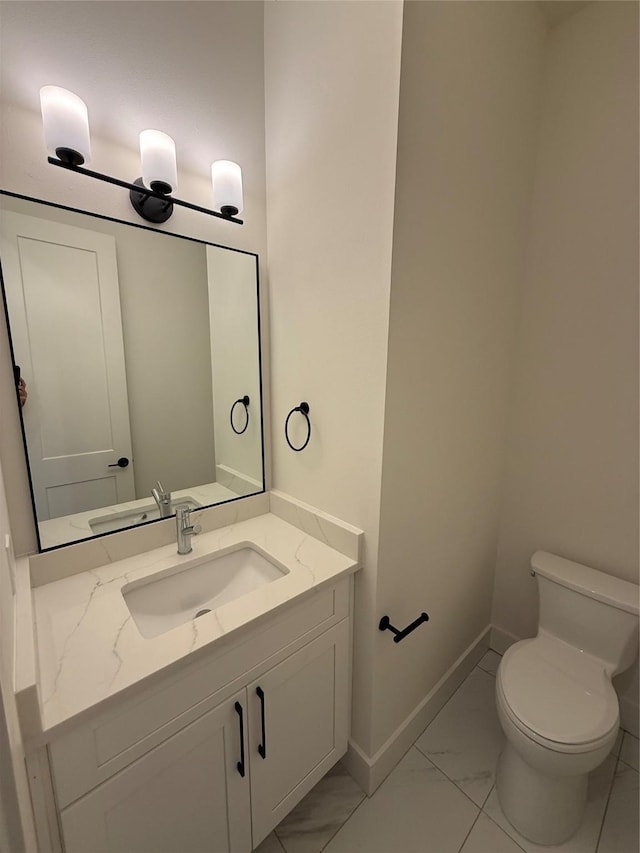 bathroom with marble finish floor, baseboards, vanity, and toilet