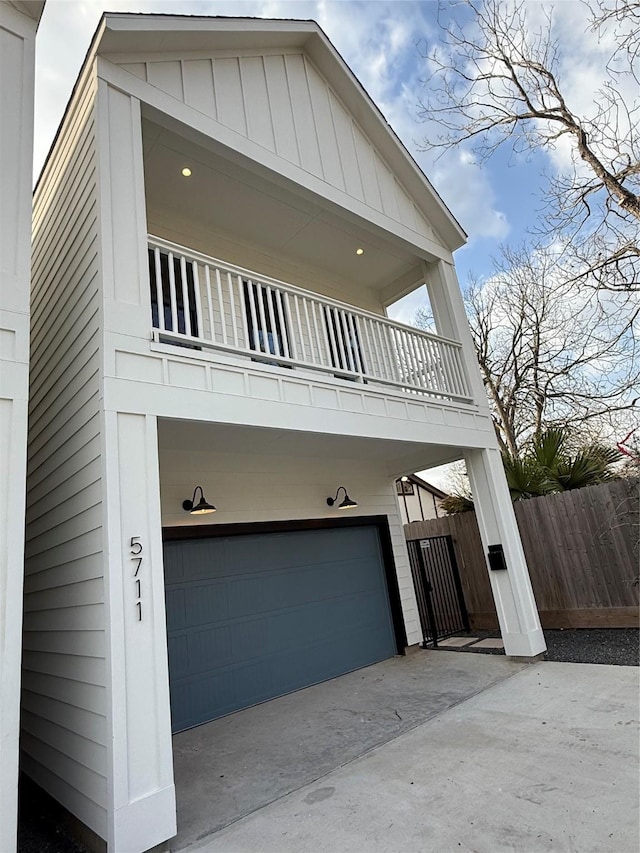 view of front of house featuring a balcony, fence, concrete driveway, a carport, and board and batten siding