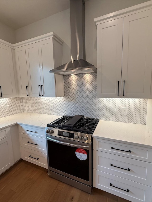 kitchen with wall chimney exhaust hood, stainless steel gas range, dark wood finished floors, and white cabinets