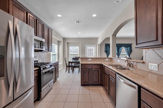 kitchen featuring light tile patterned floors, a sink, visible vents, appliances with stainless steel finishes, and backsplash