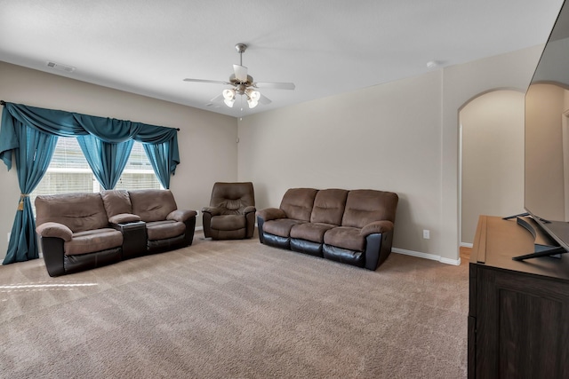 living area with light carpet, visible vents, arched walkways, baseboards, and ceiling fan