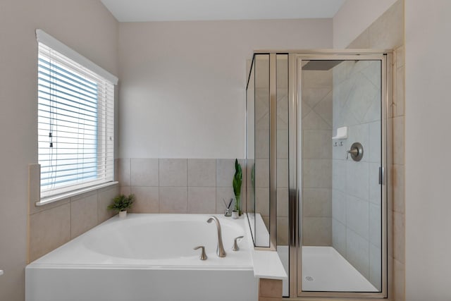 full bathroom featuring a shower stall, a bath, and a healthy amount of sunlight