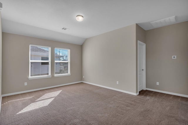 spare room featuring carpet floors, visible vents, and vaulted ceiling