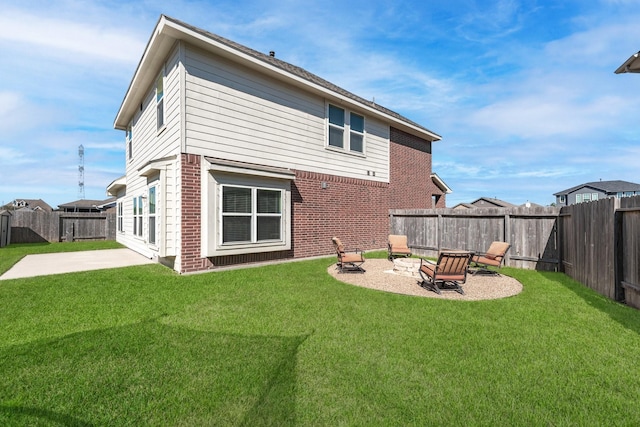 rear view of house with brick siding, a yard, an outdoor fire pit, a patio area, and a fenced backyard