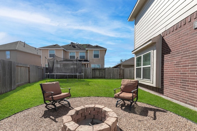 exterior space with an outdoor fire pit, a trampoline, and a fenced backyard