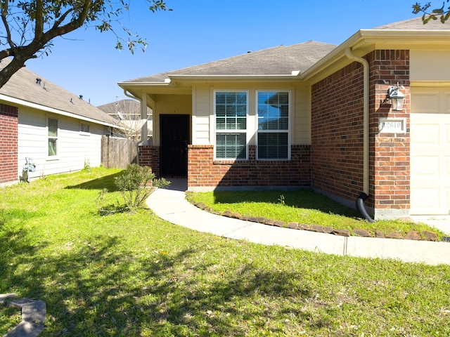 view of front facade with a front yard, brick siding, and an attached garage