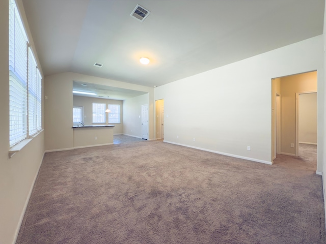 empty room with carpet floors, visible vents, vaulted ceiling, and baseboards