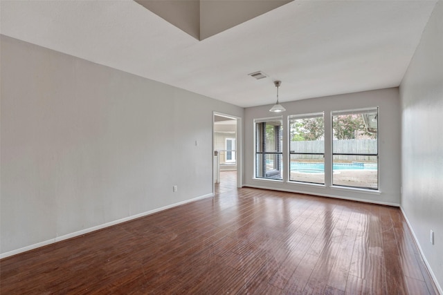 spare room featuring dark wood-style floors, visible vents, and baseboards