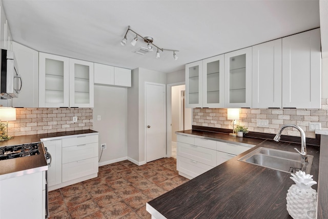 kitchen featuring dark countertops, stainless steel microwave, white cabinets, and a sink