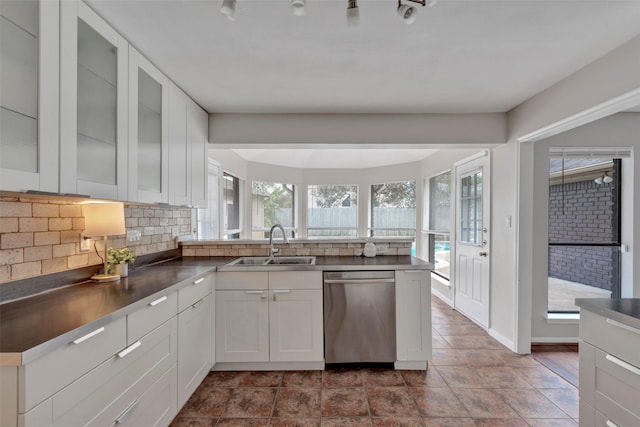 kitchen featuring a sink, a peninsula, backsplash, and dishwasher