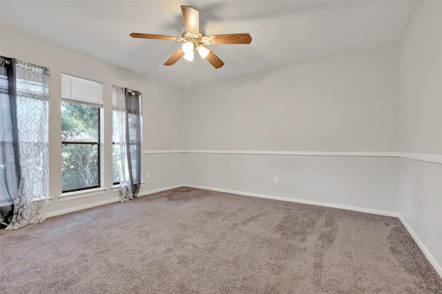 carpeted spare room featuring ceiling fan and baseboards