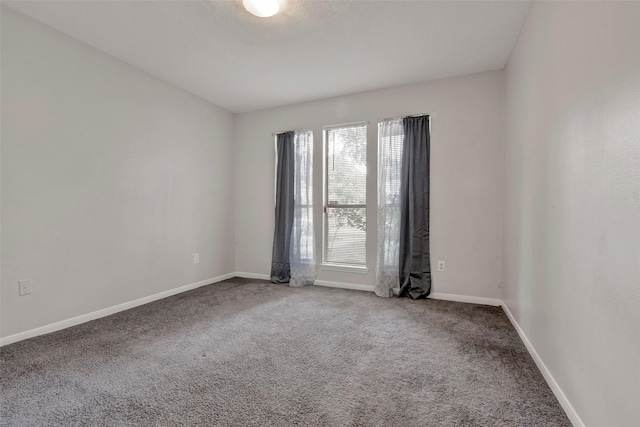 carpeted spare room featuring baseboards