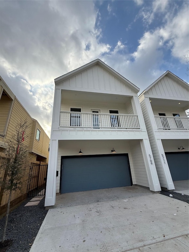 view of front of property with concrete driveway, board and batten siding, fence, a balcony, and a garage