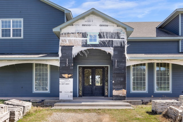 view of exterior entry with a shingled roof and french doors