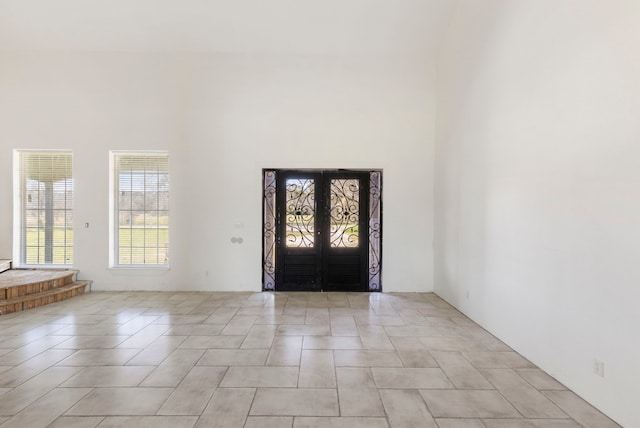 entrance foyer with french doors, light tile patterned flooring, and a towering ceiling