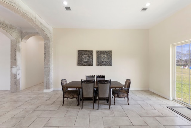 dining room with baseboards, visible vents, and arched walkways