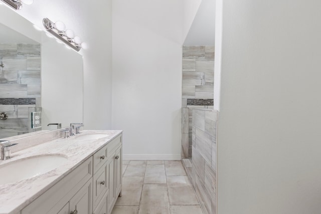 full bathroom with a sink, a tile shower, and double vanity