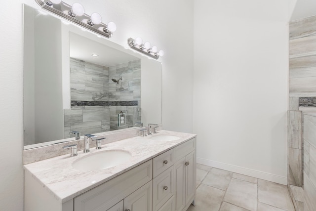 bathroom featuring double vanity, baseboards, a sink, and tiled shower