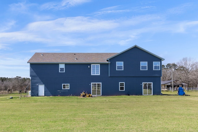 rear view of house featuring a lawn and fence