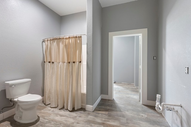 full bath featuring curtained shower, baseboards, toilet, and wood finished floors