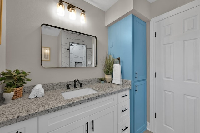 full bathroom featuring a marble finish shower and vanity