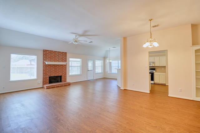 unfurnished living room featuring visible vents, baseboards, light wood-style flooring, a brick fireplace, and ceiling fan with notable chandelier