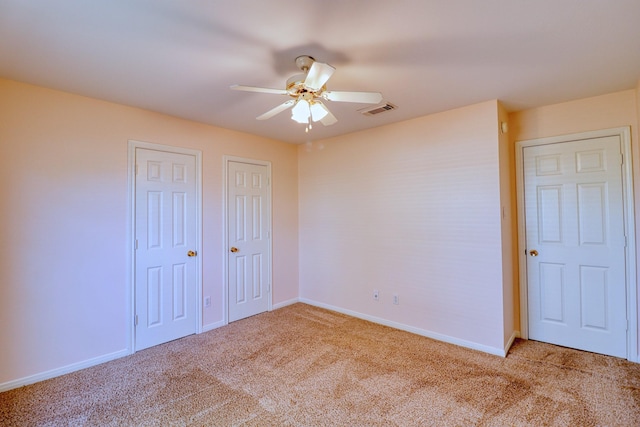 unfurnished bedroom featuring visible vents, carpet flooring, two closets, and baseboards