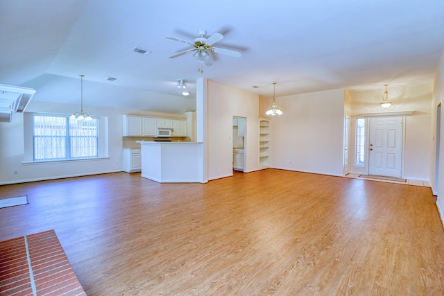 unfurnished living room with visible vents, baseboards, light wood-style floors, and ceiling fan with notable chandelier