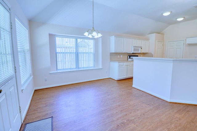 kitchen with white microwave, a chandelier, white cabinets, and vaulted ceiling