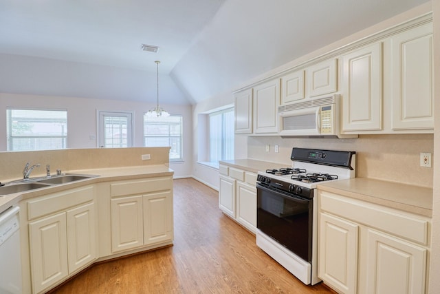 kitchen with visible vents, a sink, white appliances, lofted ceiling, and a chandelier