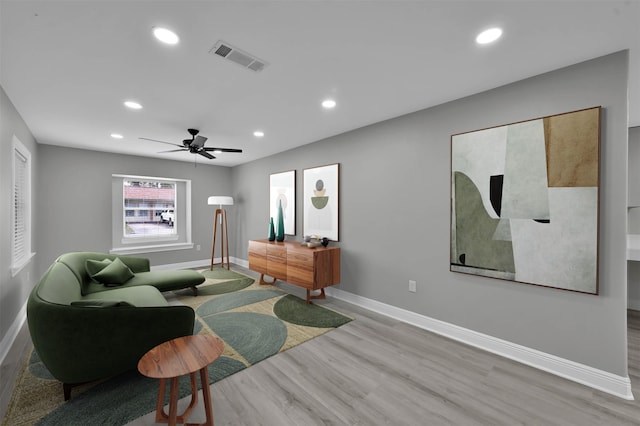 living area with recessed lighting, wood finished floors, visible vents, and baseboards