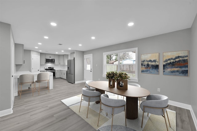 dining space featuring light wood finished floors, baseboards, and recessed lighting