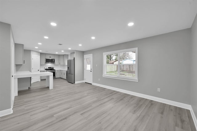 kitchen with baseboards, appliances with stainless steel finishes, gray cabinets, and recessed lighting